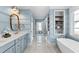 Well-lit bathroom featuring a soaking tub, blue walls, and marble floors at 1636 Sweetwater Ln, Raleigh, NC 27610