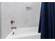 Clean bathroom showing white tub with blue shower curtain and modern marble-like tile at 1636 Sweetwater Ln, Raleigh, NC 27610