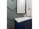 Stylish powder room showcasing a navy vanity with gold fixtures and chevron wall design at 1636 Sweetwater Ln, Raleigh, NC 27610