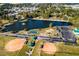 Aerial view featuring a lake with a fountain and multiple recreational areas, including ball fields and tennis courts at 174 Blue Butterfly Dr, Angier, NC 27501