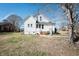 View of the back of the home with a lawn, some stairs leading to a door, and trees around at 204 N Sixth St, Mebane, NC 27302