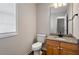 Neutral powder room with a wood vanity, granite top, and an accent mirror at 2121 Ramsgate St, Raleigh, NC 27603