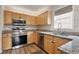 Well-lit kitchen with wood cabinets, granite countertops, stainless steel appliances, and modern fixtures at 2121 Ramsgate St, Raleigh, NC 27603