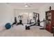 Home gym with various equipment, bright lights, and a wooden bookshelf at 2412 Toll Mill Ct, Raleigh, NC 27606