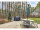 The backyard features a built-in grill and dining area on a stone patio surrounded by mature trees at 242 Sweet Pine Cir, Pittsboro, NC 27312