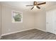 A bright bedroom with a window, fan, neutral walls, and modern gray flooring at 2606 Landis Dr, Durham, NC 27705