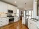 Open kitchen with stainless steel appliances, granite countertops, white cabinets, and hardwood floors at 2609 Packhouse Rd, Zebulon, NC 27597