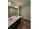 Bathroom featuring double sinks, a large mirror, and wood-look flooring, complemented by modern lighting at 28 Longdale Dr, Graham, NC 27253