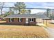 Charming brick home with black shutters and a convenient carport under a clear blue sky at 307 S Main St, Four Oaks, NC 27524