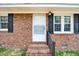 Close-up of the front entrance featuring a white door, black shutters, and brickwork for a welcoming look at 307 S Main St, Four Oaks, NC 27524