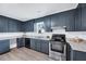 Well-lit kitchen featuring blue cabinets, stainless steel appliances, and durable countertops at 307 S Main St, Four Oaks, NC 27524