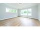 Sun-filled bedroom with hardwood floors, recessed lighting, tray ceiling, and large windows overlooking greenery at 4225 Burlington Mills Rd, Wake Forest, NC 27587