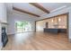 Open living room featuring hardwood floors, wooden beams, fireplace, and access to the kitchen and outdoor deck at 4225 Burlington Mills Rd, Wake Forest, NC 27587