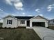 Charming single-story home with a large two-car garage, manicured lawn, and beautiful contrasting trim and shutters at 51 Robert Howe Dr, Fuquay Varina, NC 27526