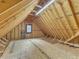 Unfinished attic space with exposed beams and subflooring with a small window at 5661 Quail Covey Ln, Wendell, NC 27591