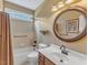 Bathroom featuring a shower-tub combo, decorative mirror, and neutral-toned tile at 5661 Quail Covey Ln, Wendell, NC 27591