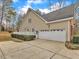 Side exterior of home with attached two-car garage and a manicured green yard at 5661 Quail Covey Ln, Wendell, NC 27591