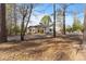Charming single-story home with light yellow siding, a gravel driveway, and mature trees at 573 Broadmoor Ct, Sanford, NC 27332