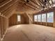 Unfinished bedroom featuring exposed rafters, plywood flooring and multiple window frames for natural light at 7429 Wexford Woods Ln, Wake Forest, NC 27587