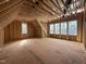 Unfinished bedroom featuring exposed rafters, plywood flooring and multiple window frames for natural light at 7429 Wexford Woods Ln, Wake Forest, NC 27587