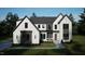 Stunning two-story home with crisp white brick, modern black trim, lush landscaping, and inviting front porch at 7429 Wexford Woods Ln, Wake Forest, NC 27587