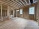 Unfinished living room featuring exposed studs, plywood flooring and large window frames for natural light at 7429 Wexford Woods Ln, Wake Forest, NC 27587