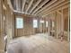Spacious unfinished living room featuring exposed studs, plywood flooring and large window frames at 7429 Wexford Woods Ln, Wake Forest, NC 27587