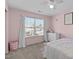 Cozy bedroom in pastel pink tones, showcasing a large window and white dresser at 749 Lake Artesia Ln, Fuquay Varina, NC 27526