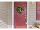 A red front door with green wreath, gold hardware and a beige storm door creates a welcoming entrance at 913 S Willhaven Dr, Fuquay Varina, NC 27526