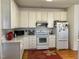 Bright kitchen features white cabinetry, appliances, hardwood floors, and a decorative flower rug at 100 Sandy Hook Way, Cary, NC 27513