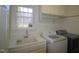 Bright laundry room featuring white cabinetry, large window, washer, utility sink and dryer at 100 Sandy Hook Way, Cary, NC 27513