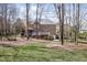 Expansive backyard featuring a two-story brick home with a deck, set amidst mature trees and greenery at 102 Shepton Dr, Cary, NC 27519