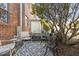 Cozy back patio with seating area, set against a red brick wall and mature tree for relaxed outdoor living at 105 Fidelity St # B24, Carrboro, NC 27510