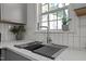 Modern kitchen sink with stainless steel faucet, white countertops, white subway tile backsplash, and window view at 1109 Sorcerer Ct Ct, Knightdale, NC 27545