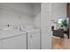 Bright laundry room with white washer and dryer, wire shelving, and view into the living room at 1109 Sorcerer Ct Ct, Knightdale, NC 27545