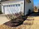 Exterior shot of the garage featuring white door and manicured flowerbeds, enhancing curb appeal at 111 Kalmia Dr, Durham, NC 27703