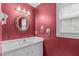 Bathroom with a white vanity, a gilded mirror, and red walls at 115 Perth Pl, Durham, NC 27712