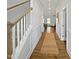 Hallway features wood floors, white walls, and a staircase with wood and white trim; the hallway is warmly lit at 120 Whistling Way # Cary Traditiol, Lillington, NC 27546