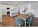 Open concept kitchen and dining area with white cabinets, stainless appliances, and modern dining set with wood floors at 120 Whistling Way # Cary Traditiol, Lillington, NC 27546