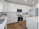 Modern kitchen boasts white cabinets, stainless steel appliances, granite counters, and wood-look floors at 120 Whistling Way # Cary Traditiol, Lillington, NC 27546