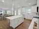 Open-concept kitchen with island, stainless appliances, and view to dining area; the floors are wood laminate at 120 Whistling Way # Cary Traditiol, Lillington, NC 27546
