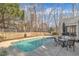 Relaxing backyard featuring a fenced in-ground pool, mature trees, and patio dining at 149 Winterberry St, Clayton, NC 27527