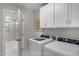 Well-equipped laundry room featuring modern washer and dryer, white cabinetry, and bathroom access at 1783 Ballard Rd # Apex Georgian, Fuquay Varina, NC 27526