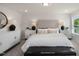 This primary bedroom is light and airy, and features neutral decor with a tufted headboard and modern side tables at 1803 Ballard Rd # Holly Craftsman, Fuquay Varina, NC 27526
