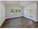 Dining area with a chandelier, large windows, wood-look floors, and a door leading outside at 1803 Ballard Rd # Holly Craftsman, Fuquay Varina, NC 27526