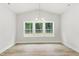 This dining area features large windows with backyard views, vaulted ceiling, chandelier, and vinyl flooring at 1803 Ballard Rd # Holly Craftsman, Fuquay Varina, NC 27526