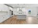 Bright kitchen boasts white cabinetry, stainless hood, and island with quartz counters, complemented by wood flooring at 1803 Ballard Rd # Holly Craftsman, Fuquay Varina, NC 27526