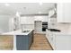 This kitchen features an island with bar seating, stainless appliances, white cabinetry, and wood flooring at 1803 Ballard Rd # Holly Craftsman, Fuquay Varina, NC 27526