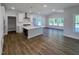 Open-concept kitchen with white cabinets, a center island, stainless steel appliances, and wood-look floors at 1803 Ballard Rd # Holly Craftsman, Fuquay Varina, NC 27526