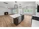 Kitchen island with sink, dishwasher, and seating area in an open-concept layout with fireplace at 1849 Ballard Rd # Holly Georgian, Fuquay Varina, NC 27526